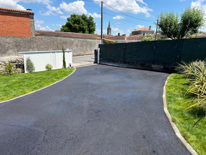 Résalisation d'une allée en enrobé à chaud avec bordurettes en béton, seuil, et portail coulissant alu blanc.