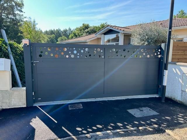 Portail alu gris coulissant avec décors.